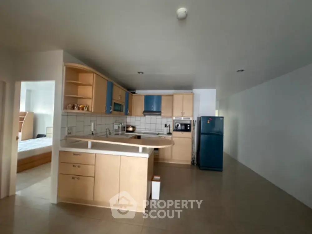 Spacious open kitchen with modern appliances and adjacent bedroom view