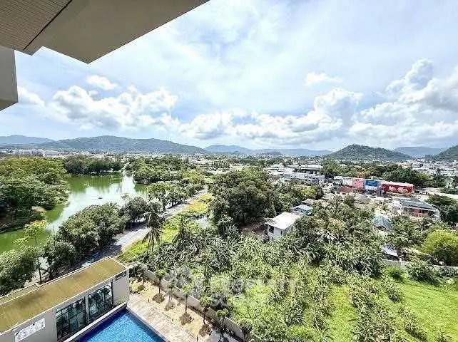 Stunning panoramic view from high-rise balcony overlooking lush greenery and serene pool.