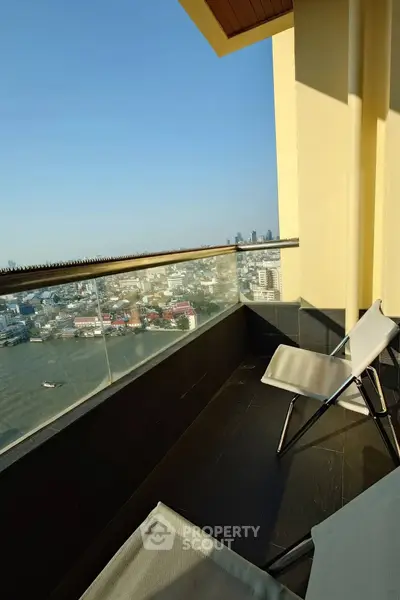 Stunning balcony view with modern seating overlooking city skyline and river, perfect for relaxation.