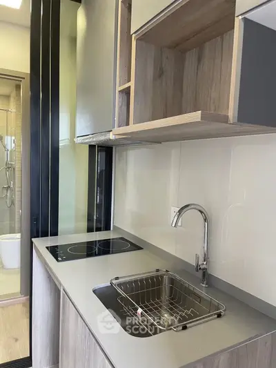 Modern kitchen with sleek design, featuring induction cooktop and stainless steel sink.