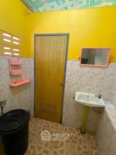 Charming bathroom with vibrant yellow walls and pink accents, featuring a pedestal sink and tiled flooring.