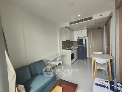 Modern open-layout living room with kitchen in a stylish apartment, featuring sleek furniture and contemporary design.