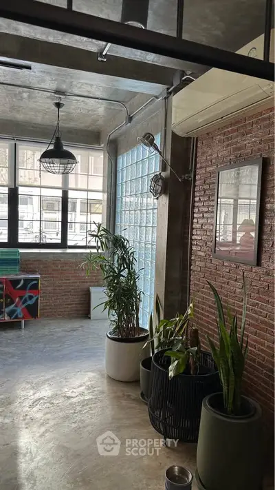 Stylish industrial loft with exposed brick and large windows, featuring modern decor and natural light.