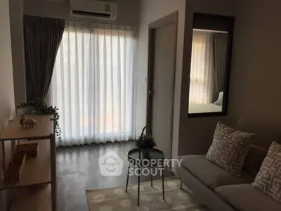 Cozy living room with modern decor and natural light through sheer curtains.