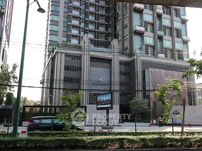 Modern high-rise building exterior with urban street view and lush greenery.
