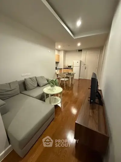 Modern living room with sleek furniture and open kitchen layout in a cozy apartment.