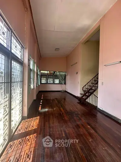 Spacious living room with wooden floors and large windows, perfect for natural light.