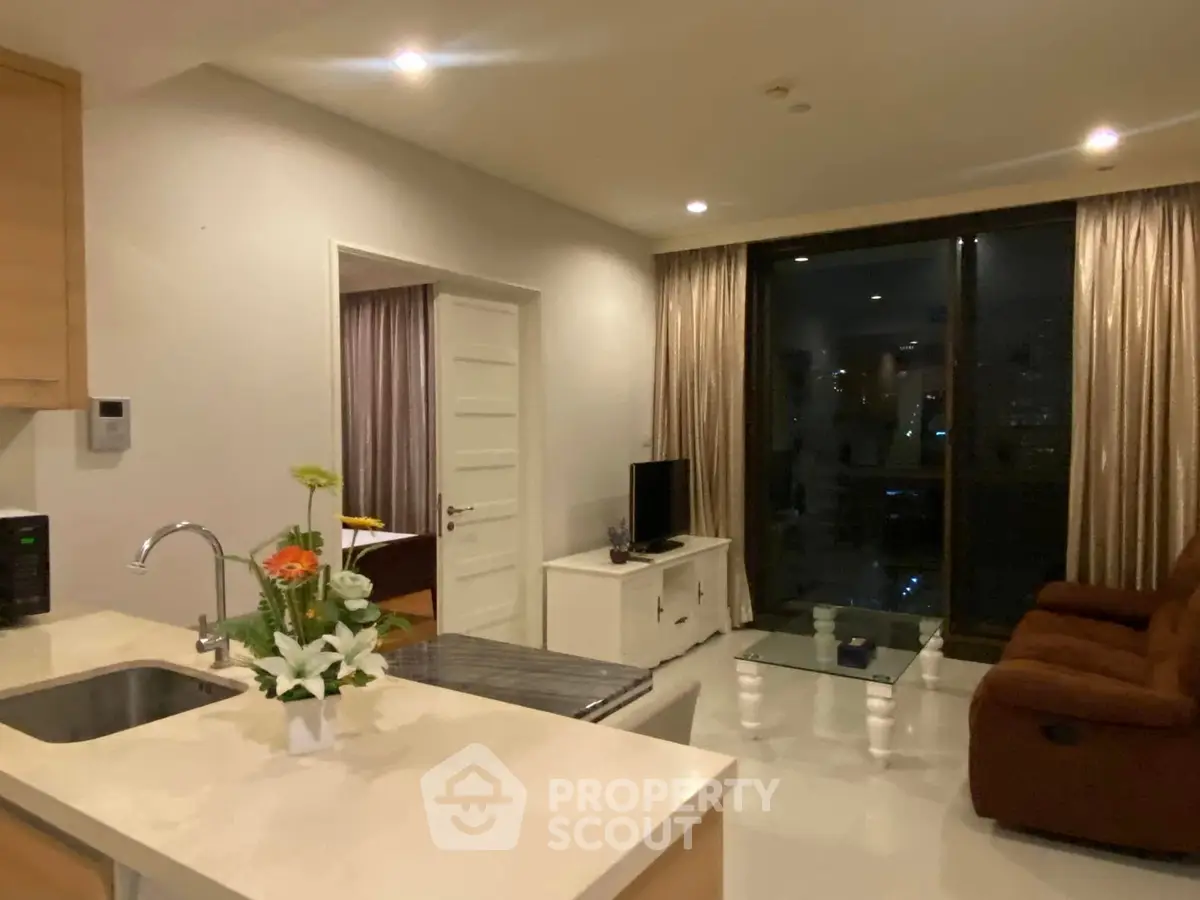 Modern living room with open kitchen and cozy seating area, perfect for relaxation and entertainment.