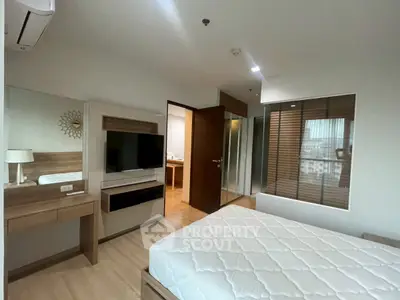 Modern bedroom with stylish decor and large window offering natural light.