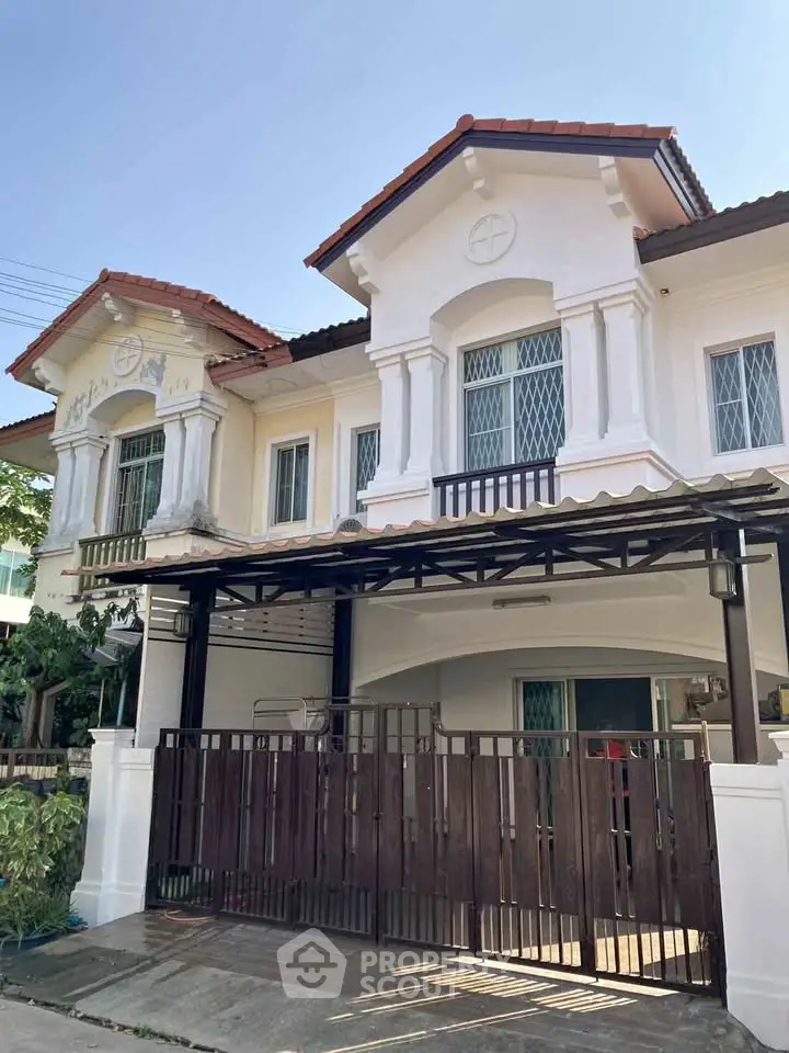 Charming two-story house with classic architecture and gated entrance in a serene neighborhood.