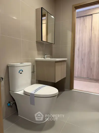 Modern bathroom with sleek fixtures and neutral tones, featuring a stylish vanity and contemporary toilet.