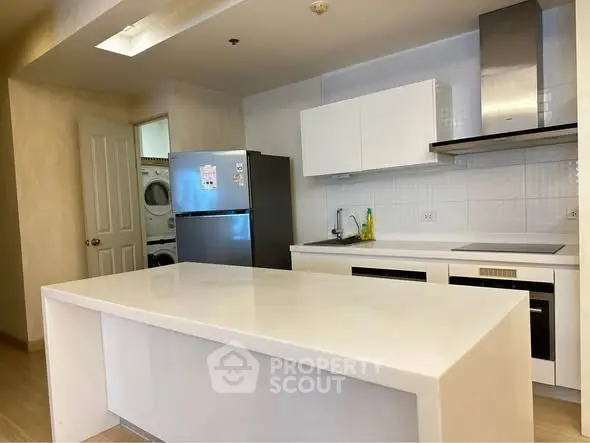 Modern kitchen with sleek white countertops and built-in appliances in a stylish apartment.