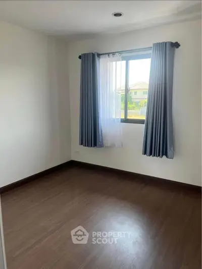 Spacious empty bedroom with large window and elegant curtains