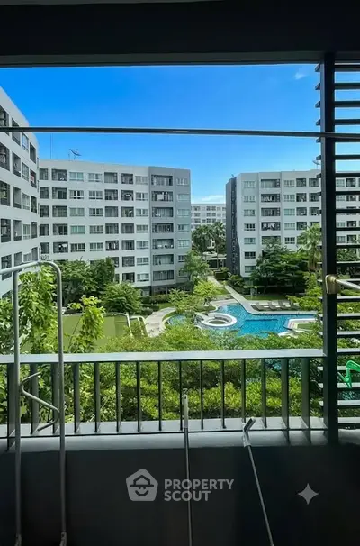 Stunning view from balcony overlooking lush garden and pool in modern apartment complex.