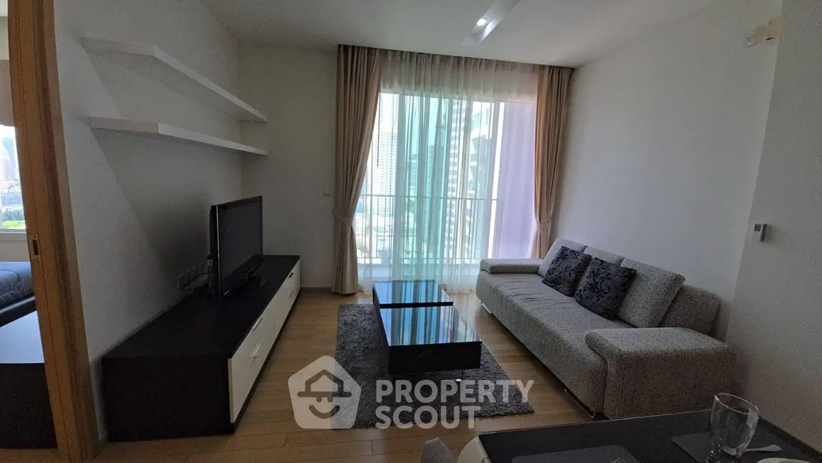 Modern living room with sleek furniture and large window offering city view.