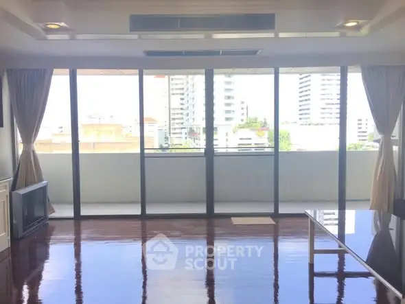 Spacious living room with large windows and city view, perfect for modern urban living.