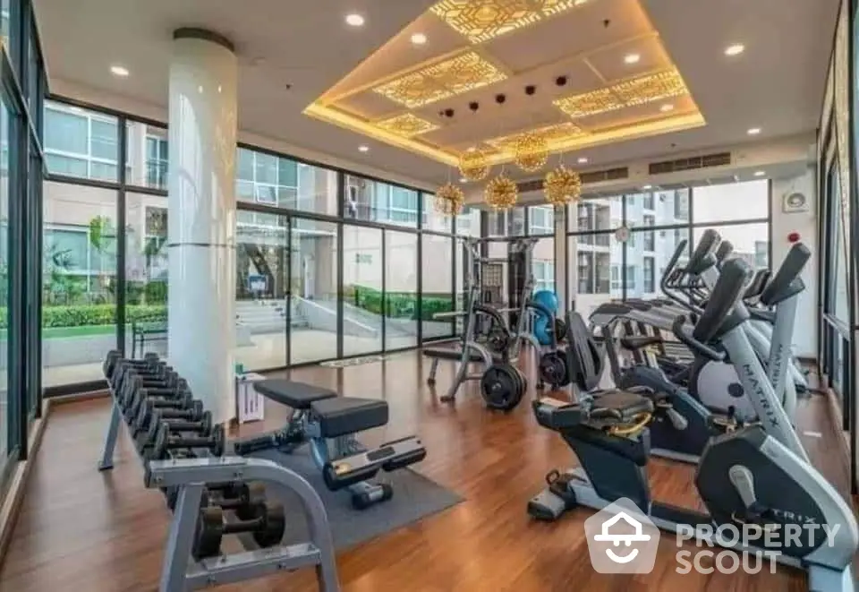 Luxurious gym with modern equipment and large windows in upscale residential building.