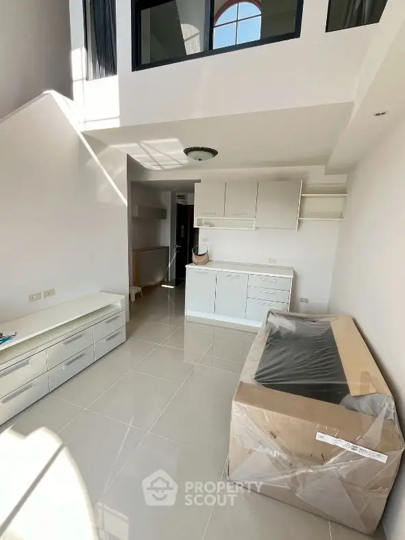 Modern loft-style living room with high ceiling and sleek white furniture