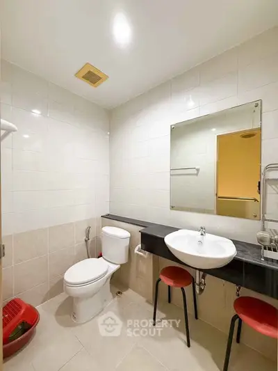 Modern bathroom with sleek fixtures and neutral tiles, featuring a large mirror and contemporary design.