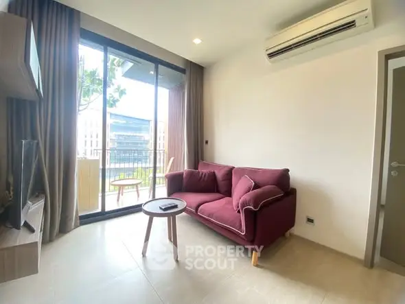 Modern living room with balcony view, featuring a stylish red sofa and air conditioning.