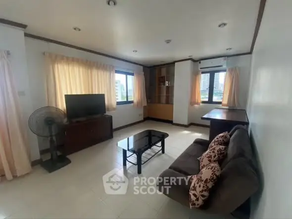 Spacious living room with modern decor and large windows offering city views.