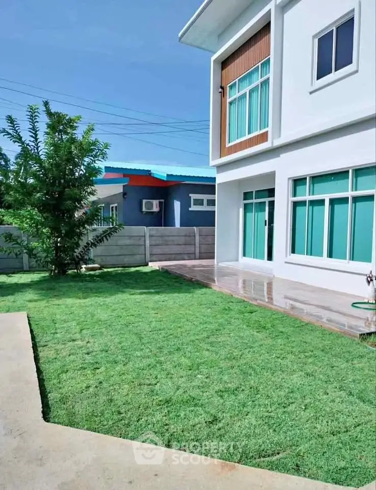 Modern two-story house with spacious green lawn and large windows, perfect for family living.
