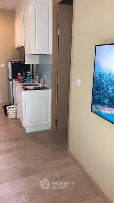 Modern compact kitchen with sleek cabinetry and integrated appliances in a cozy apartment setting.