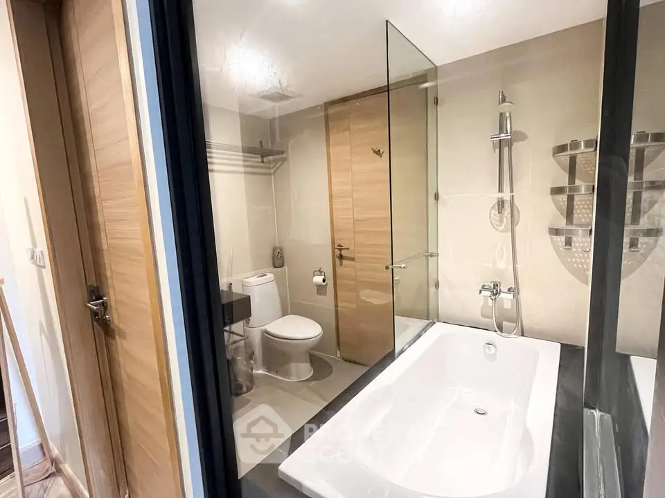 Modern bathroom with glass shower and bathtub in sleek design.
