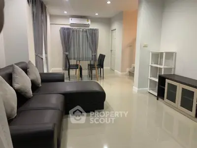 Modern living room with sleek furniture and dining area in a stylish home.