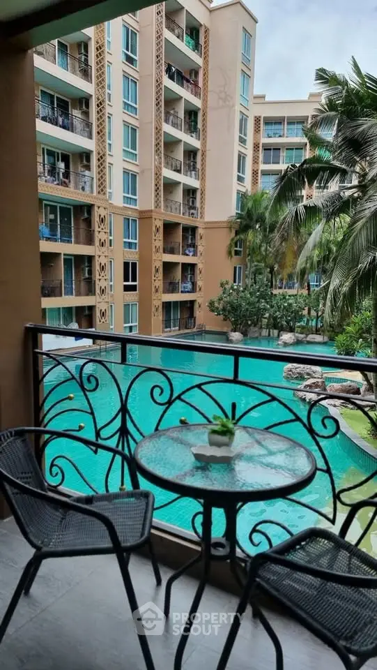 Luxurious balcony view overlooking a stunning pool and modern apartment complex, perfect for relaxation.