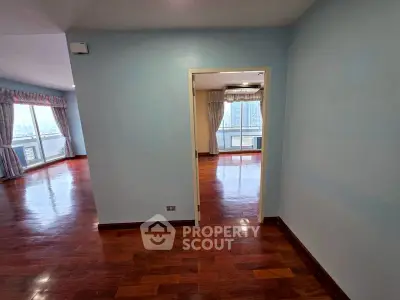 Spacious apartment with hardwood floors and large windows offering city views.