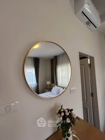 Chic bedroom with round mirror and elegant decor, featuring a cozy bed and stylish curtains.