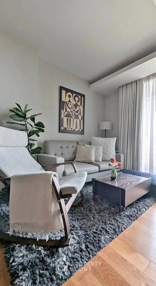 Stylish living room with modern furniture, cozy rug, and large window for natural light.