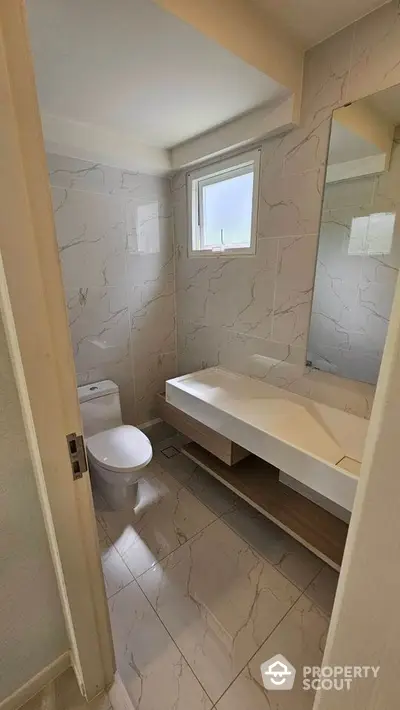 Modern bathroom with sleek design and natural light, featuring elegant marble tiles and contemporary fixtures.