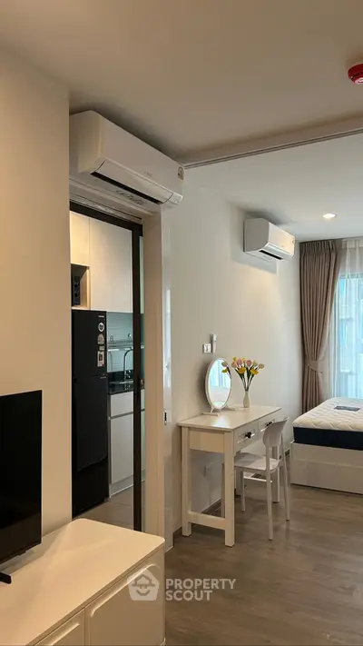 Modern studio apartment with sleek kitchen and cozy living area, featuring air conditioning and natural light.