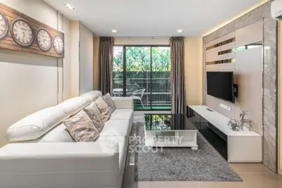 Modern living room with sleek design and garden view, featuring a white sofa and stylish decor.
