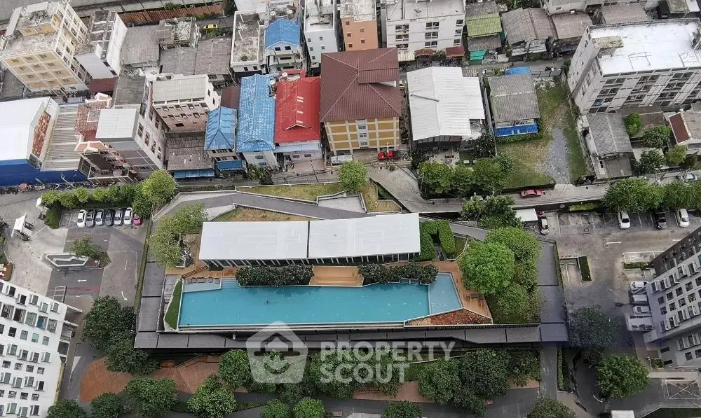 Stunning aerial view of modern rooftop pool with lush greenery in urban setting.