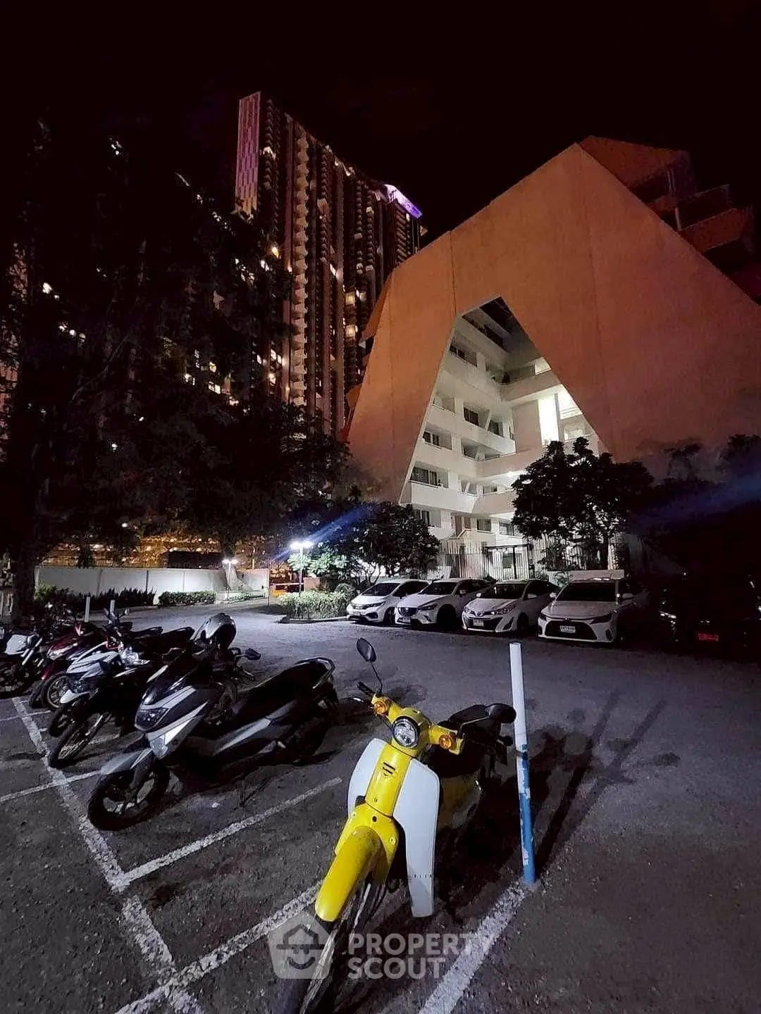 Modern urban apartment building with night view and parking area.