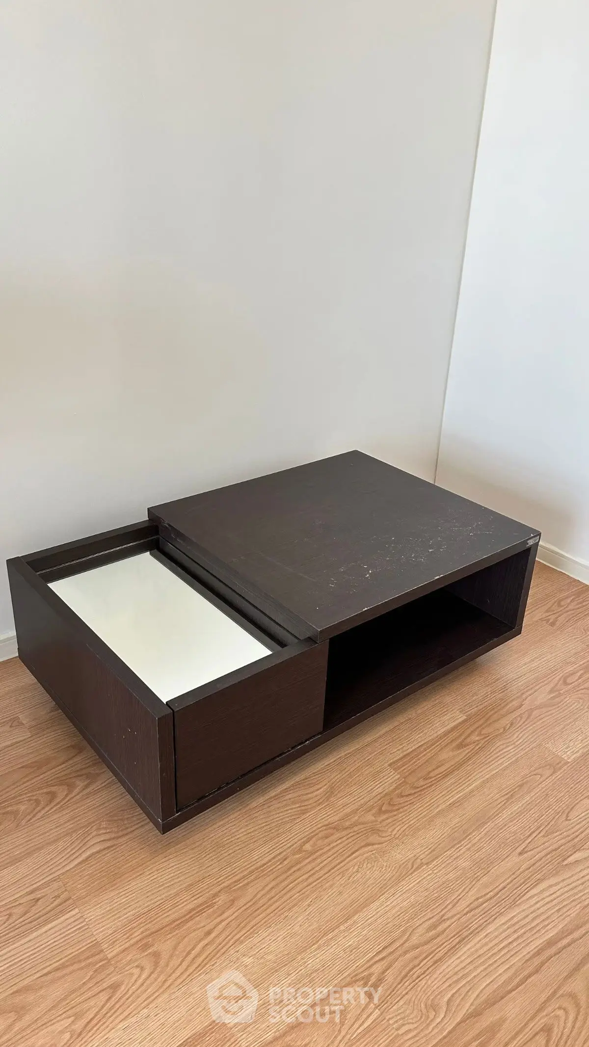 Modern wooden coffee table with sliding drawer on laminate flooring