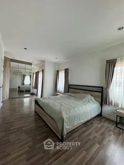 Spacious bedroom with modern decor and large windows for natural light
