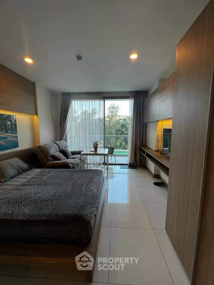 Modern studio apartment with cozy bed and living area, large window offering scenic view