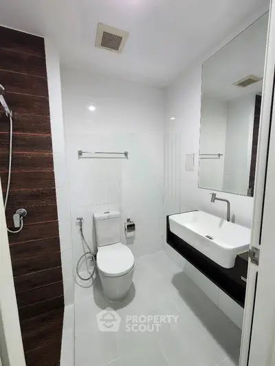 Modern bathroom with sleek fixtures and minimalist design, featuring a wall-mounted sink and contemporary shower.