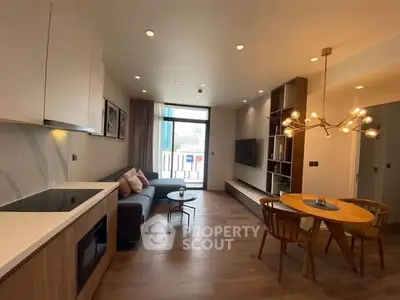 Modern living room with open kitchen, stylish lighting, and cozy seating area in a contemporary apartment.