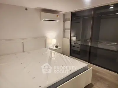 Modern bedroom with sleek design, featuring a large bed, built-in wardrobe, and air conditioning.