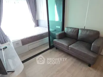 Modern compact living room with cozy sofa and glass partition to bedroom, featuring sleek wooden flooring.