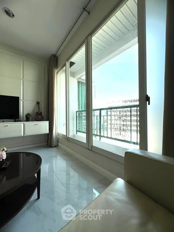 Spacious living room with large windows offering a stunning city view, modern decor, and abundant natural light.