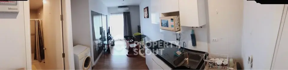 Modern apartment interior with open kitchen and cozy living area, featuring stylish furniture and natural light.
