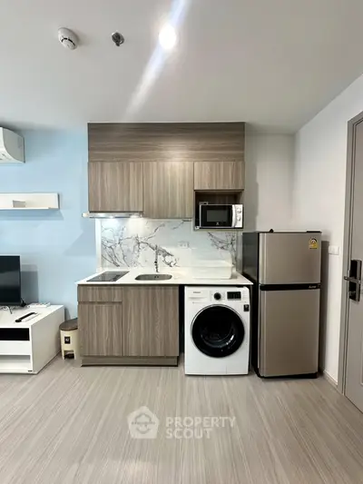 Modern compact kitchen with integrated appliances and stylish cabinetry in a contemporary apartment.
