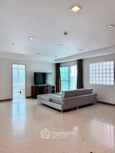 Spacious modern living room with sleek furniture and large windows offering natural light.
