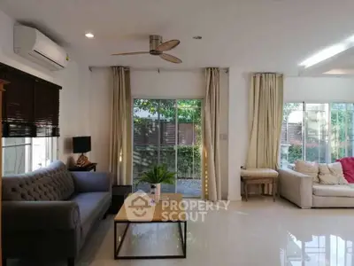 Spacious living room with modern decor and large windows offering garden view